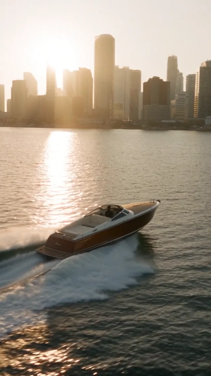 Gold engraved sunglasses in macro on black, intercut with a yacht crossing Biscayne Bay at sunset.